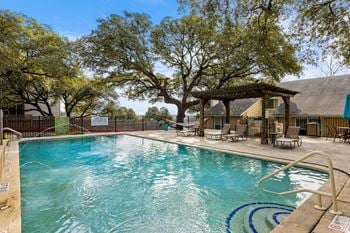 A large swimming pool surrounded by trees and lounge chairs.